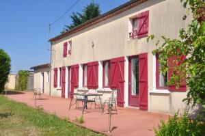 Grande Maison au Calme في La Merlatière: مبنى بأبواب حمراء وطاولة وكراسي