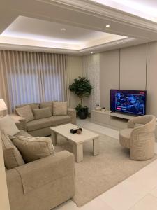 een woonkamer met banken en een flatscreen-tv bij Alarjan Dream in Riyad