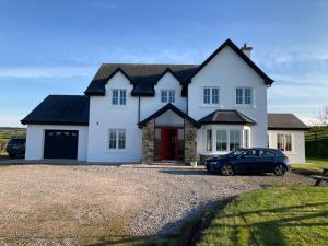 a white house with a car parked in the driveway at Hunthill in Tulach an Iarainn