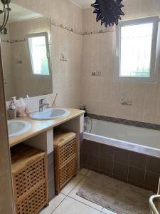ジニャックにあるMaison agréable proche de Saint Guilhem-le-Desert 2 chambresの洗面台2つ、浴槽1つ、鏡1つを備えたバスルーム