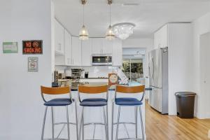 Una cocina con gabinetes blancos y una barra con sillas. en Tranquil Pool Home in Hollywood Close to Beach Airport, en Hollywood