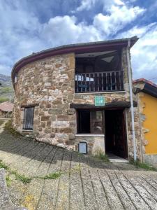 an old stone building with a balcony on it at Albergue de Aciera in Agüeras