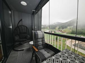 a room with a chair and a balcony with a view at Bjelašnica Ski View Apartment in Bjelašnica