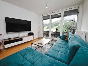 a living room with a blue couch and a flat screen tv at Bjelašnica Ski View Apartment in Bjelašnica