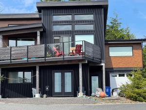 a black house with two chairs on a balcony at Slack tide suite in Ucluelet