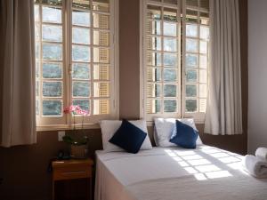 a bed in a bedroom with two windows at Hotel Municipal Araraquara in Araraquara
