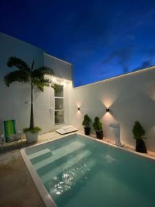 a swimming pool at night with potted plants at casa blanca in Beberibe