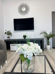 a vase of white flowers on a glass table in a living room at Anastasia Dragonul Roșu Spitalul Fundeni in Dobroeşti