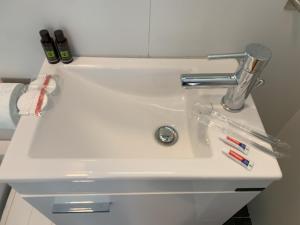 a white sink with tooth brushes and a faucet at Hippodrome Cute - Blue in Thessaloniki