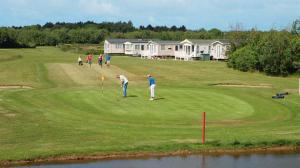 a group of people playing golf on a golf course at 9 Fairway, Hopton Holiday Park - Three bedroom, sleeps 6, kitchen, lounge and dining area - Minimum 3 night breaks in Hopton on Sea