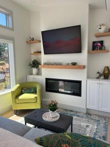 a living room with a fireplace and a tv on the wall at Serene Forest Retreat in Sooke