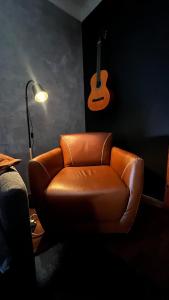 a brown leather chair in a room with a guitar on the wall at Boutique Flat com Banheira Lareira e Piscina Aquecida in Campos do Jordão