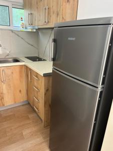 a stainless steel refrigerator in a kitchen with wooden cabinets at Hotel JF Dhërmi in Dhërmi