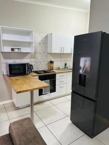 a kitchen with a black refrigerator and a table at Koshoka Residence in Windhoek