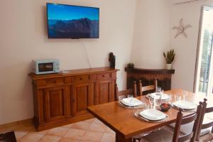 a dining room with a table and a tv on the wall at Chalet Nausicaa in Lanzo dʼIntelvi