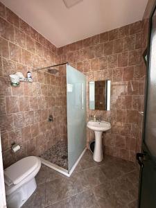 a bathroom with a shower and a toilet and a sink at Hotel JF Dhërmi in Dhërmi +10 photos