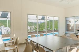 a dining room with a table and chairs and windows at Ámbar Roca / Rodadero in Rodadero
