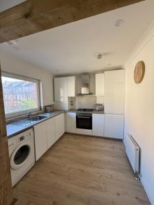 a kitchen with white cabinets and a washer and dryer at Luxurious 2 bedroom, 8 mins from city centre in Glasgow
