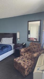 a hotel room with a bed and a chair and a mirror at Queen Bed Hotel Room 202 in Amarillo