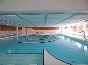 a large swimming pool with blue water in a building at Maison Duplex Confort-Coté Cour et Jardins-Centre Gare in Amiens