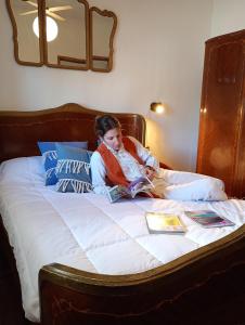 une femme assise sur un lit en train de lire un livre dans l'établissement Vivienda de alquiler por dia completa en Junin, à Junín