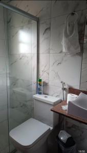 Un baño blanco con inodoro y ducha. en Chalé Beira Rio Cipó, en Serra do Cipo