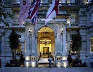a man standing in front of a building with flags at The Langham London in London