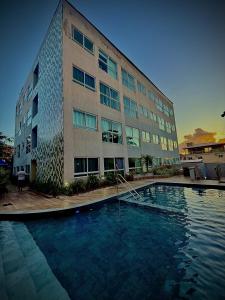 a building with a swimming pool in front of a building at Sossego do Porto Galinhas Flats in Porto De Galinhas