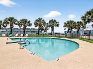 a swimming pool with palm trees in the background at Bayfront Kontiki 107 in Rockport