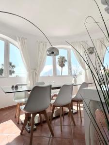 ein Esszimmer mit Tisch und Stühlen und Fenstern in der Unterkunft Relaxdiversión en Villa Piscina bbq y cocina ext in Calpe + 26 Fotos