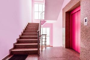 Una escalera con una puerta rosa y una escalera. en Hotel O ShamRock INN, en Jaipur
