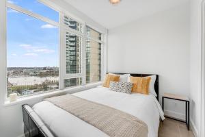 a bedroom with a bed and a large window at Luxury 2-Bedroom Condo with Floor-to-Ceiling Windows and City Views in Vancouver