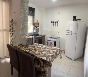 a kitchen with a table and a white refrigerator at Apartamento Aconchego in Botucatu