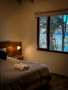 une chambre avec un lit avec une grande fenêtre dans l'établissement EL SUSURR0, à Villa Pehuenia