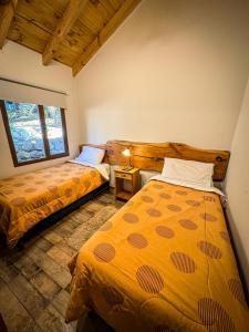 une chambre avec deux lits et une fenêtre dans l'établissement EL SUSURR0, à Villa Pehuenia