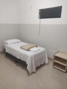 a bed in a white room with a tv at Hotel Marques in Coração de Jesus