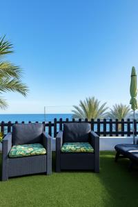 dos sillas en un césped con el océano en el fondo en A Dream On The Beach Sun Club, en Playa del Águila