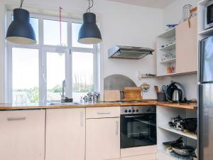 a kitchen with white cabinets and blue pendant lights at 4 person holiday home in Grenaa in Grenå