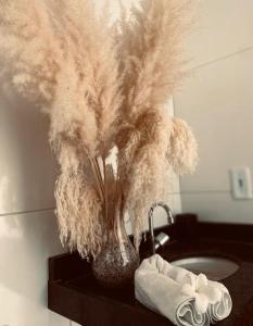 a vase filled with feathers sitting on a bathroom sink at casa blanca in Beberibe