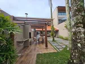 patio con tavolo e sedie sotto un pergolato in legno di Casa pé na areia na Praia de Juquehy a São Sebastião