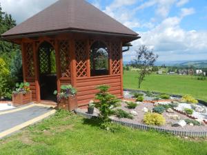 a wooden gazebo in a field with a garden at Pokoje Gościnne Pod Gubałówką in Nowe Bystre