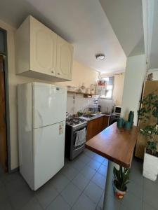 a kitchen with a white refrigerator and a wooden table at Apartamento Terminal - Consorcio Libertador in San Juan