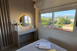 a bedroom with a window and a bed and a mirror at Residencial Barin - Perto de TUDO! LZN Hospedagens in Santa Maria