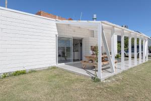 a white building with a porch with a bench at Ola Santa in Colonia Chapadmalal