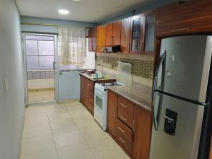 a kitchen with wooden cabinets and a refrigerator at Amplio departamento para grupo de 10 personas con 3 dormitorios in Cuenca