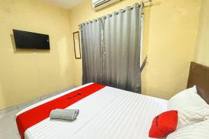- une chambre avec un lit doté d'une couverture rouge et d'une télévision dans l'établissement RedDoorz near RS Hermina Tangerang,  5 autres photos