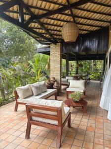 un patio avec des canapés et des tables sous un toit dans l'établissement Casa Charme 5 Suítes e areá gourmet - Praia da Pipa by PipaCharme, à Pipa