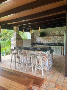 un patio avec un bar et des tabourets sur un patio dans l'établissement Casa Charme 5 Suítes e areá gourmet - Praia da Pipa by PipaCharme, à Pipa