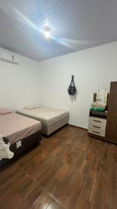 a bedroom with two beds and a wooden floor at Casa com dois quartos e piscina in Barreirinhas