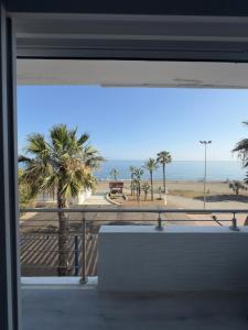 a window with a view of a beach and palm trees at Apartamento VistaSol in Rincón de la Victoria